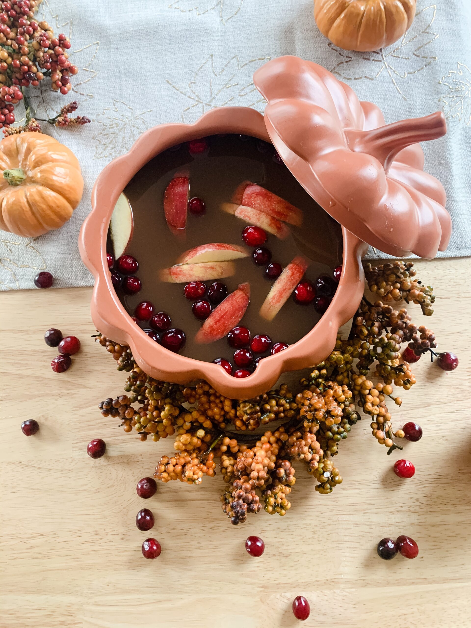 harvest punch with cranberries and apples served in a ceramic pumpkin bowl