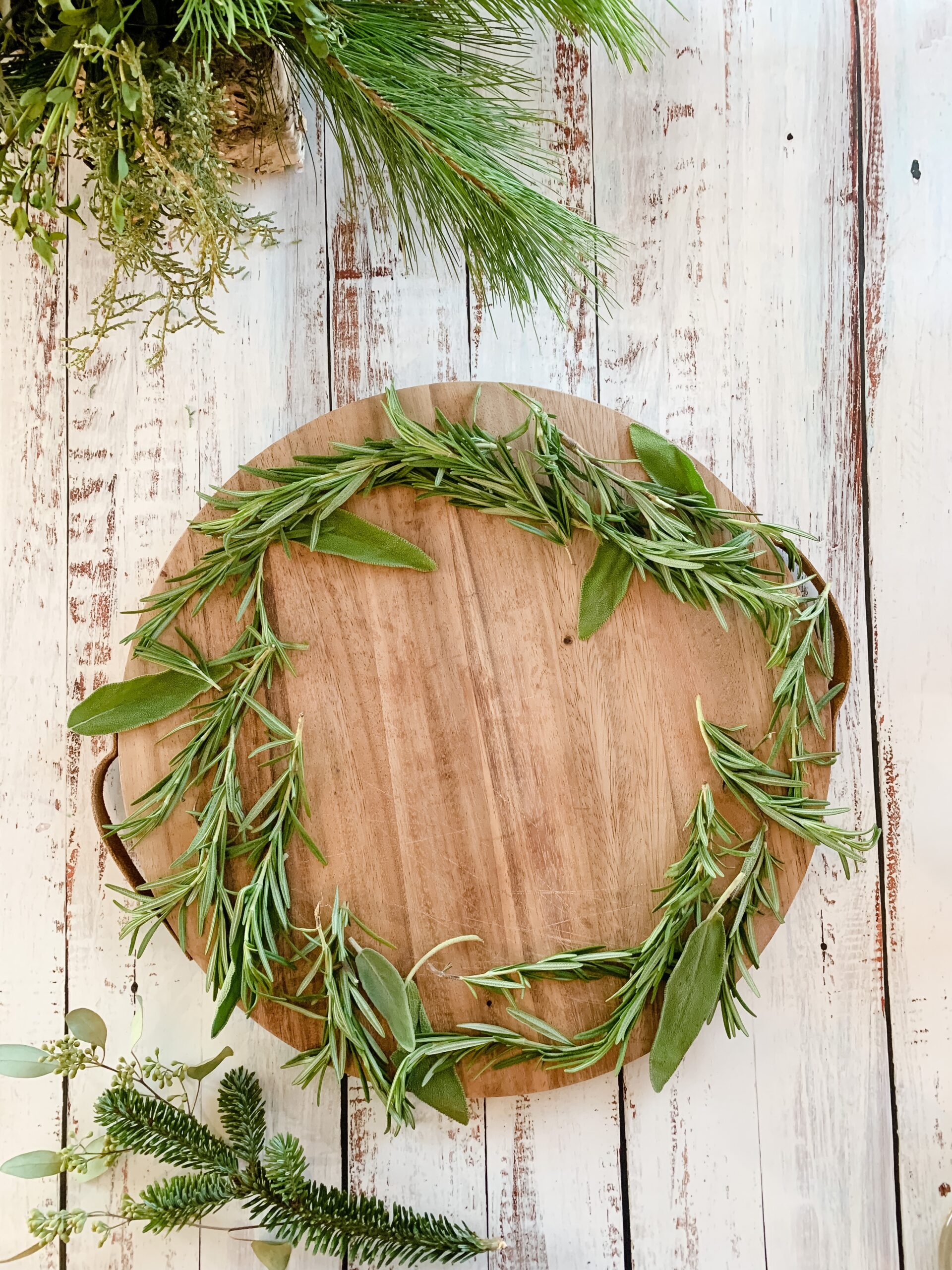 wooden serving board with sage and rosemary sprigs
