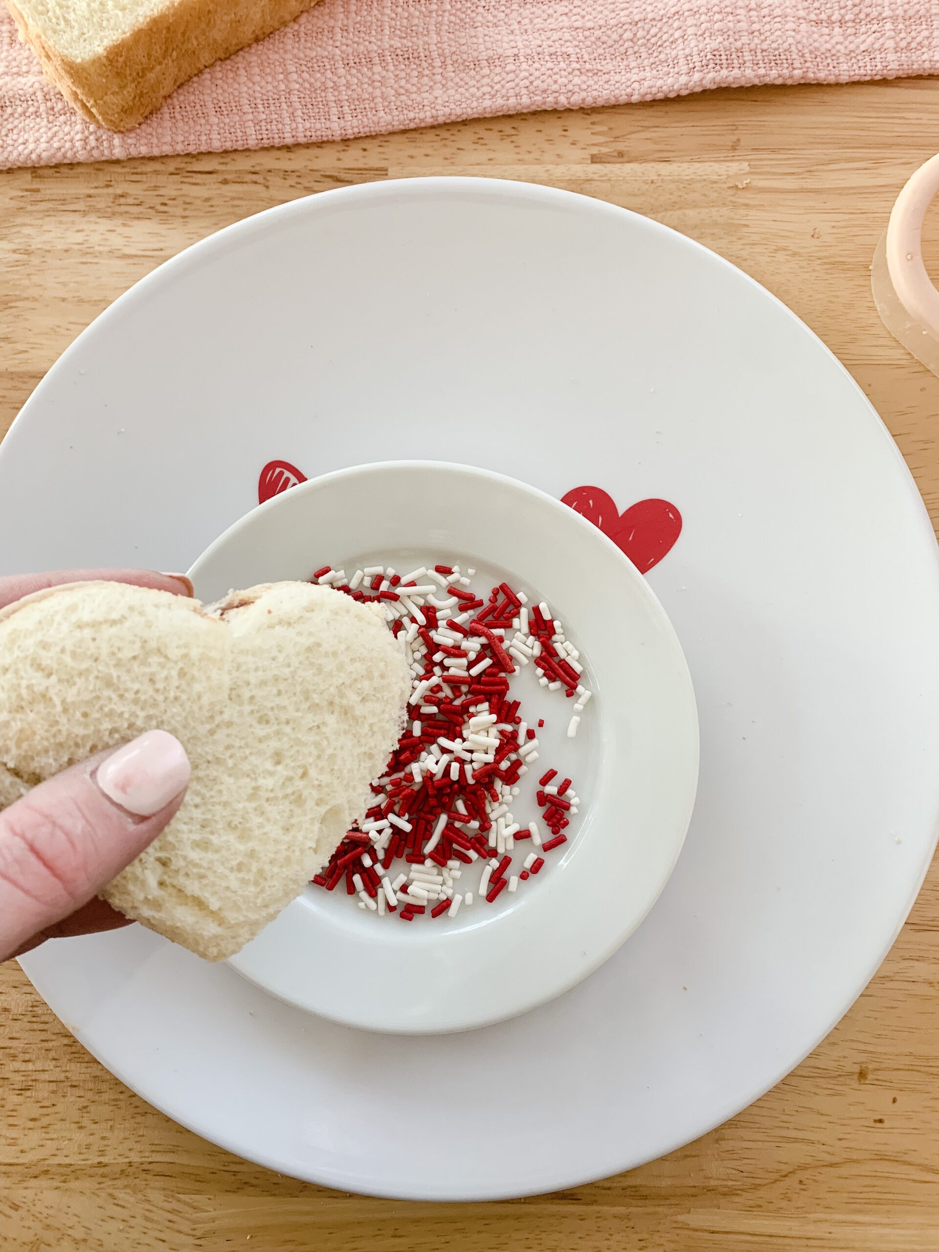 dipping a sandwich into red and white sprinkles for Valentine's Peanut Butter and Jelly
