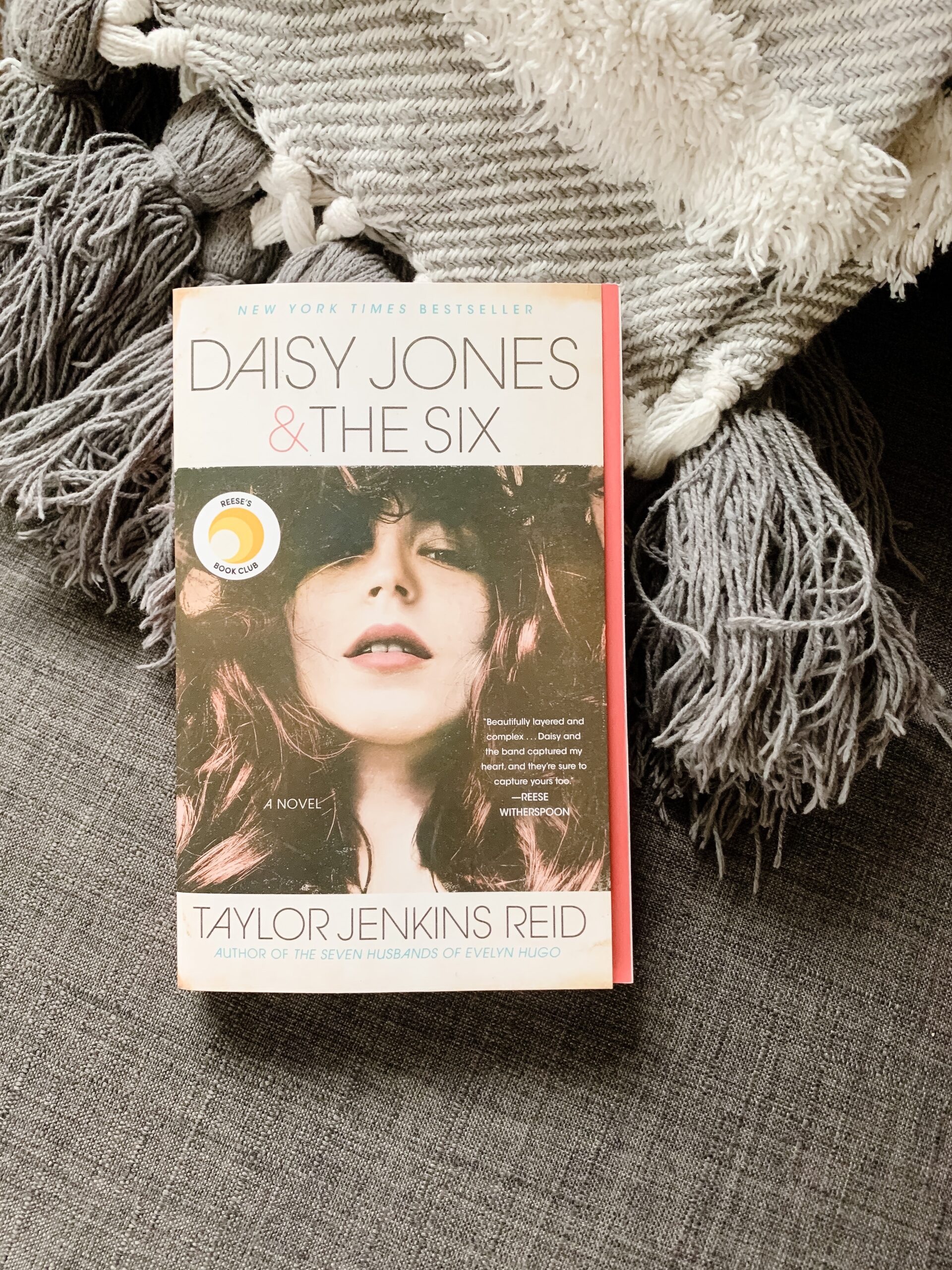 Image of the novel Daisy Jones and the Six, by Taylor Jenkins Reid. Book with image of rock star sits on a chair