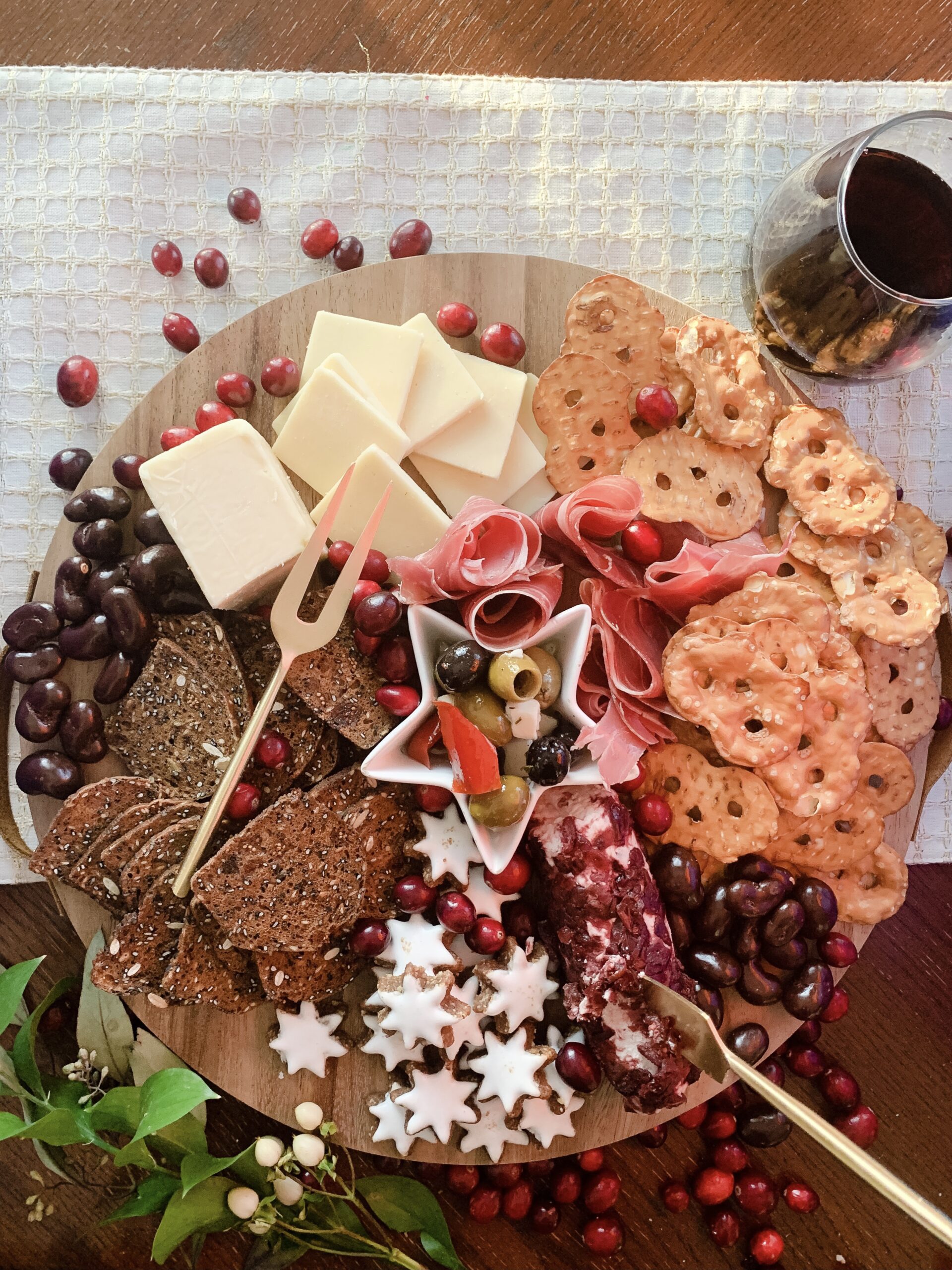 Aldi holiday charcuterie board on a budget. Meats and cheeses on a wooden board surrounded by cranberries. 