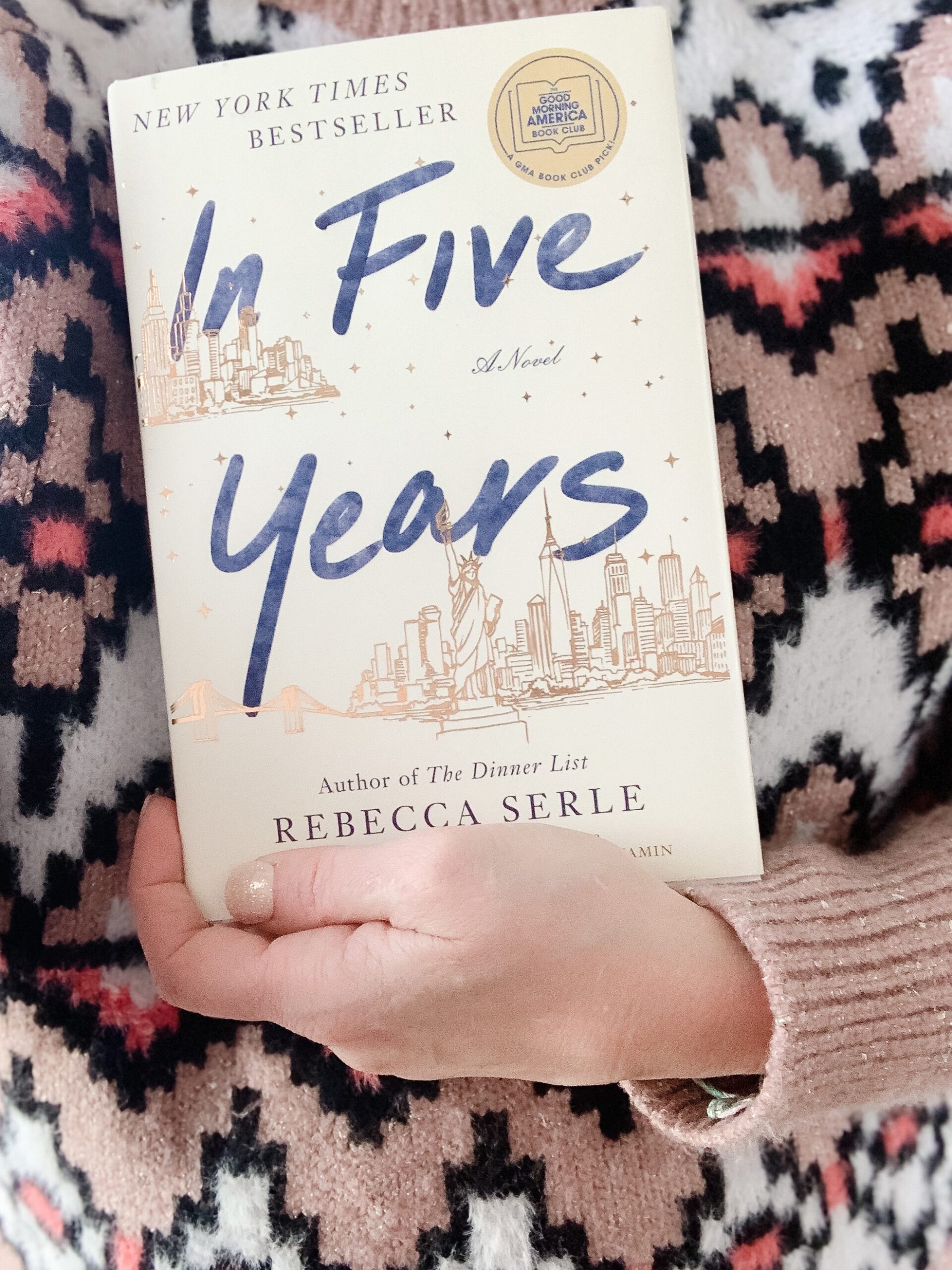 woman in fair isle sweater holding the novel In Five Years by Rebecca Serle. Book-A-Month Reading Challenge