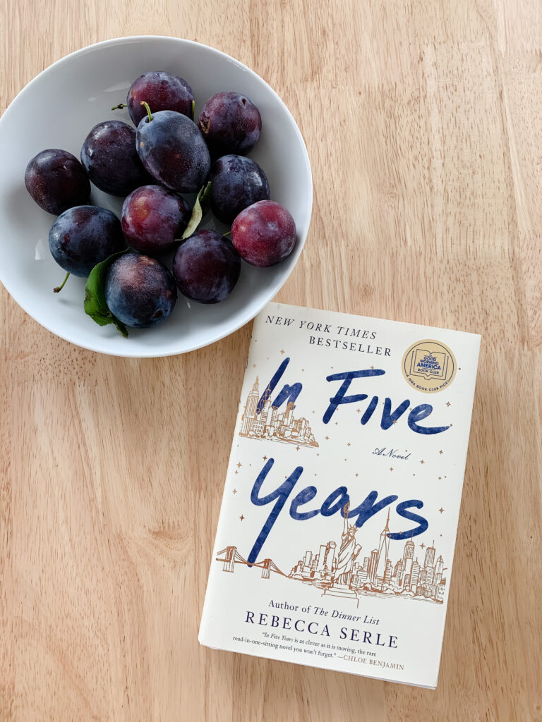 Novel In Five Years by Rebecca Serle on table next to plums